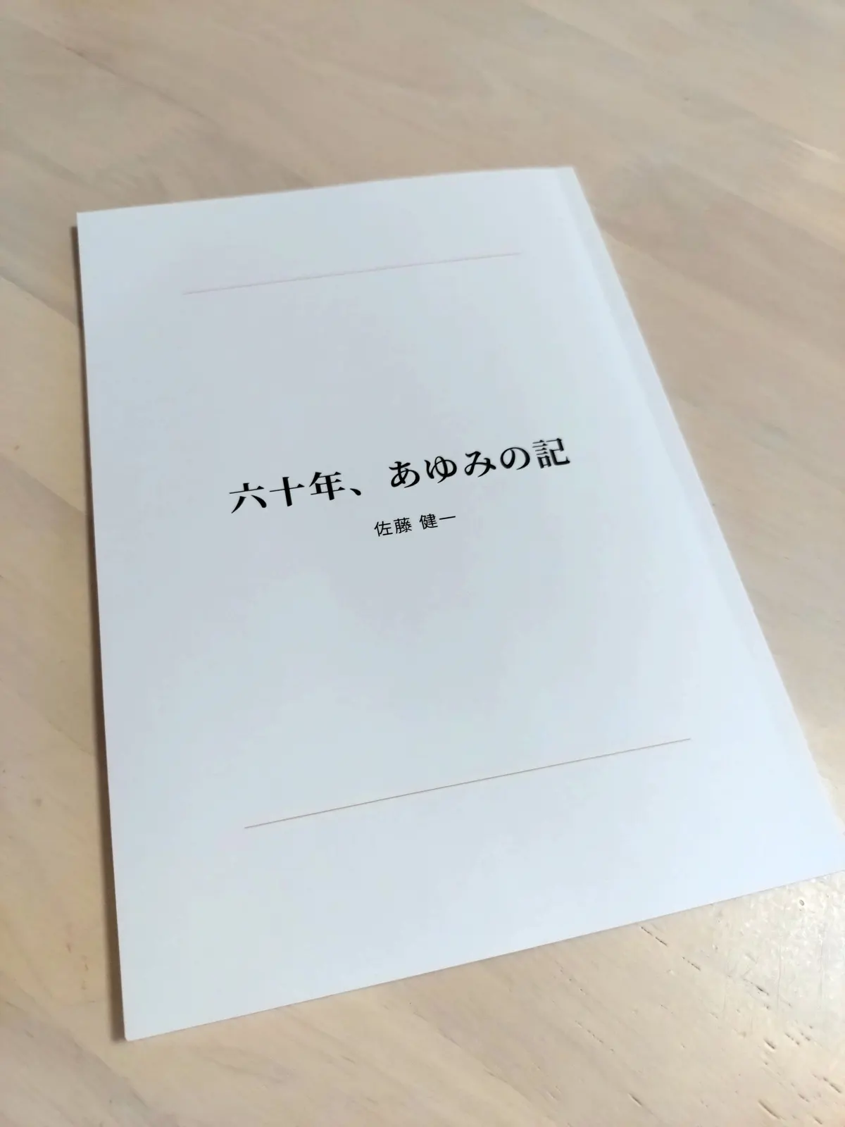 届いた本の表紙。白い表紙に「六十年、あゆみの記」と著者名